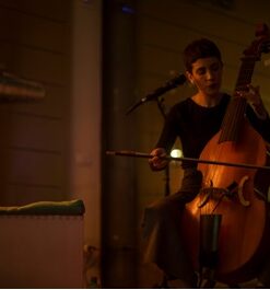 Violoncellista esegue brano davanti a un microfono.